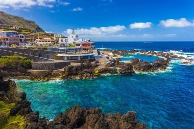 Vista da costa da Madeira e de uma piscina de água salgada rodeada de rochas vulcânicas
