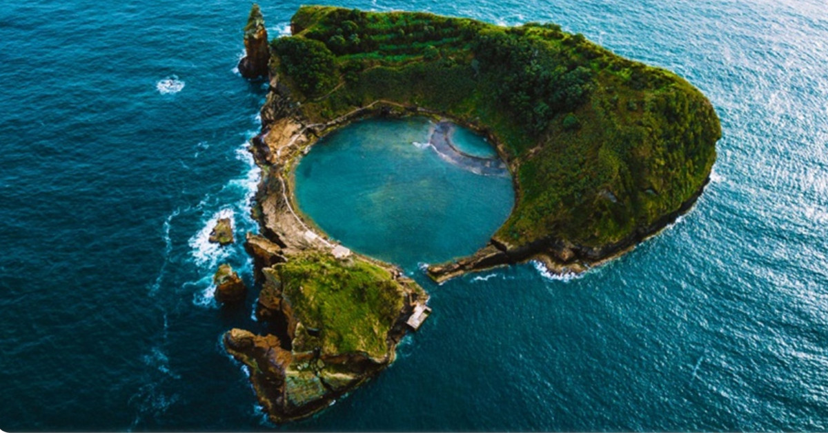 Vista aérea de vulcão cuja cratera está submersa pelo mar e os seus limites formam uma ilha circular