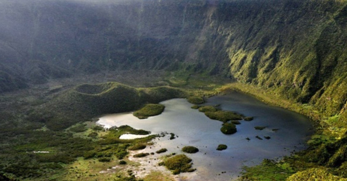 Vista superior de uma cratera de vulcão verdejante com lagoa